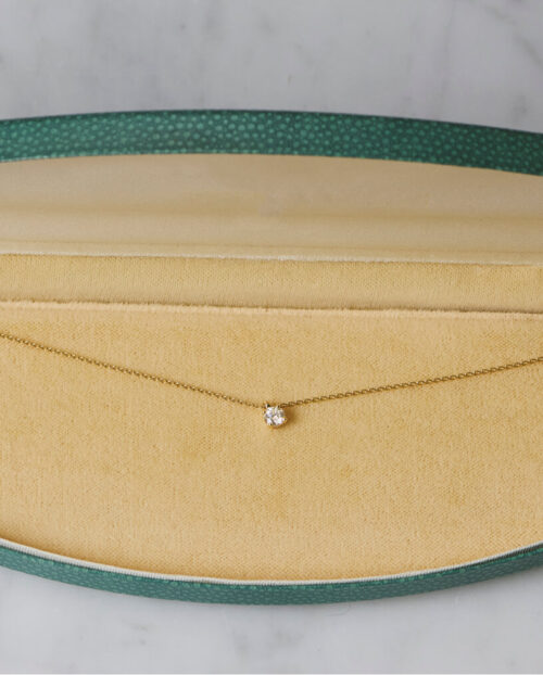 A white diamond pendant on chain in a blue leather box