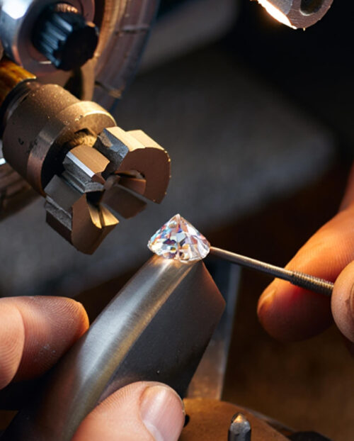A white natural diamond being cut between someone's fingers