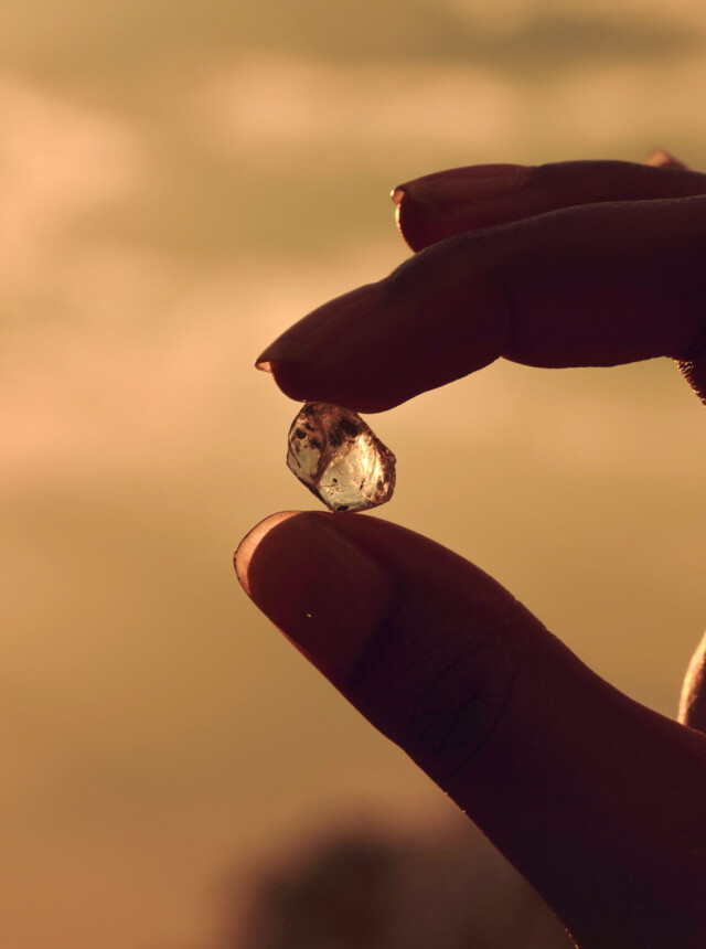 Fingers holding a natural diamond